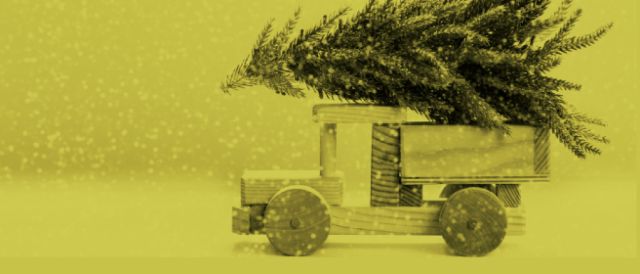 Ein Holzspielzeug-Lastwagen hat einen Tannenbaum auf dem Dach und liefert ihn aus. Das ganze Bild ist gelb-grün eingefärbt.