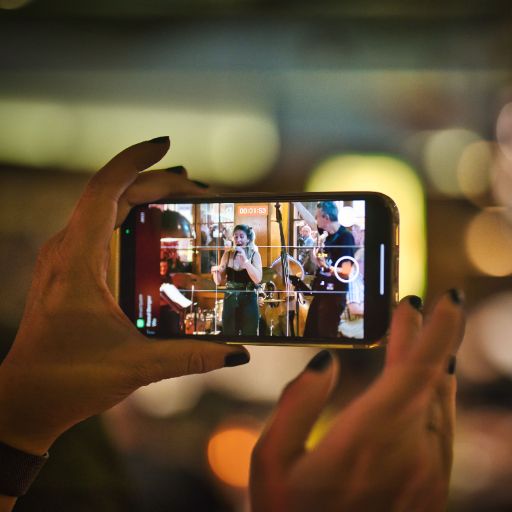 Nahaufnahme Musikfestival Em Bebbi sy Jazz: zwei Frauenhände halten ein Smartphone und filmen eine Band